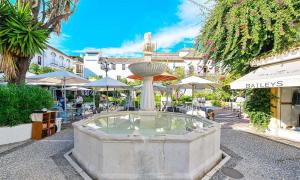 una fuente en medio de una calle con mesas y sombrillas en Apartamento en casco antiguo - Cerca de la playa, en Marbella
