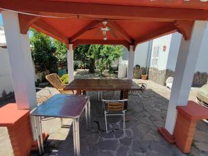 eine Terrasse mit einem Tisch und Stühlen unter einem roten Dach in der Unterkunft Casa al mare con giardino vicino a Roma in Torvaianica