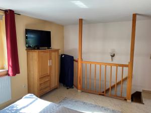 a bedroom with a tv on a wooden dresser with a bed at Ferienwohnung Lotte am Tennisplatz in Görlitz