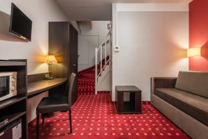 a hotel room with a couch and a desk and a staircase at Hôtel des Deux Avenues in Paris