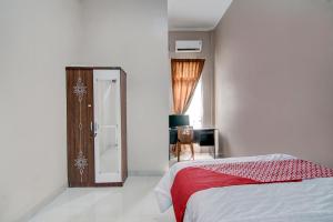 um quarto com uma cama com um cobertor vermelho em OYO 92806 Penginapan Geby Syariah em Pekanbaru