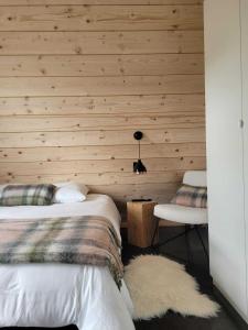 a bedroom with wooden walls and a bed and a chair at Les Deltas du Lac in Chambon-sur-Lac +40 photos