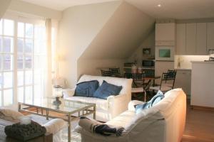 uma sala de estar com dois sofás brancos e uma mesa em Albatros D2 em De Haan