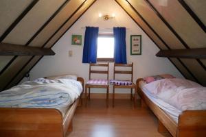 um quarto com duas camas e duas cadeiras num sótão em Zeepolder I 38 em De Haan