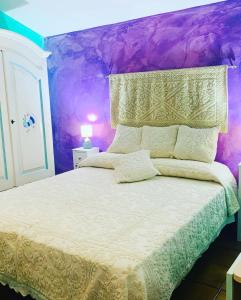 een slaapkamer met een bed met een paarse muur bij Da Ida in Bosa