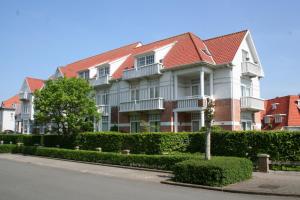a large white house with a red roof at Albatros C0 in De Haan
