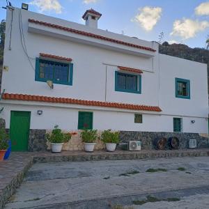 une maison blanche avec des plantes en pot devant elle dans l'établissement Casa Mami Carmen Telde, Las Palmas, à Balcon de Telde