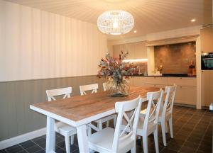 a kitchen with a wooden table and white chairs at Edelweis in De Haan