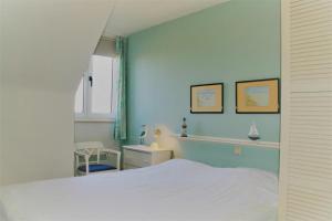 um quarto com uma cama branca e uma parede azul em Golf & Beach B3 em De Haan