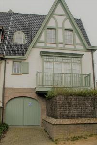 een groot huis met een groene garagedeur bij Tristan in De Haan