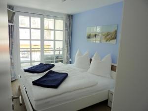 ein weißes Bett mit zwei blauen Kissen darauf in der Unterkunft Residenz am Balmer See - BS 58 mit Wellnessbereich in Balm