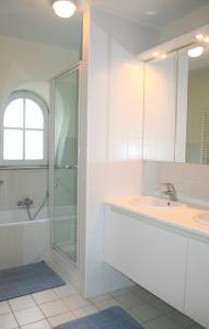 uma casa de banho branca com um chuveiro e um lavatório. em Tristan em De Haan