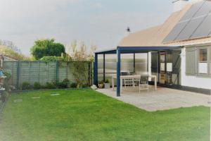 ein Haus mit einer Terrasse mit einem Tisch im Hof in der Unterkunft Zeewind I 46 in Bredene