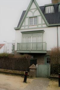 een groot wit huis met een groen hek bij Tristan in De Haan