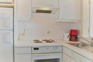 cocina blanca con fogones y fregadero en Golf & Strand C2, en De Haan