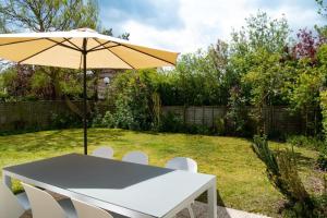 una mesa blanca con un paraguas en un patio en Zeewind II 112, en Bredene