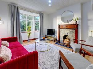 ein Wohnzimmer mit einem roten Sofa und einem Kamin in der Unterkunft Terracotta House I Executive House I Parking and Pet Friendly I eco-Short Term Let by SILVA in Clapham