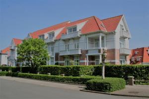 a large white building with a red roof at Albatros B0 in De Haan