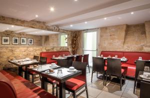restauracja ze stołami, krzesłami i czerwonymi budkami w obiekcie Hôtel des Deux Avenues w Paryżu