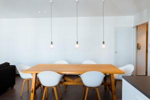 uma sala de jantar com uma mesa de madeira e cadeiras brancas em Beau Sejour A1 em De Haan