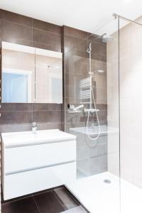 uma casa de banho com um lavatório branco e um chuveiro em Beau Sejour A1 em De Haan