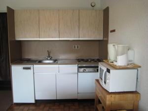 a kitchen with white cabinets and a sink and a microwave at Appartement Huez, 1 pièce, 4 personnes - FR-1-405-48 in L'Alpe-d'Huez