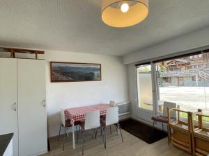 comedor con mesa, sillas y ventana en Appartement Huez, 1 pièce, 4 personnes - FR-1-405-123 en L'Alpe-d'Huez