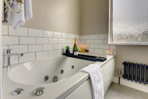 eine weiße Badewanne mit einer Flasche Wein im Bad in der Unterkunft Terracotta House I Executive House I Parking and Pet Friendly I eco-Short Term Let by SILVA in Clapham