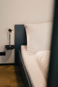 a bed with a white pillow and a lamp at CELLA Apartments **** in Zell im Wiesental