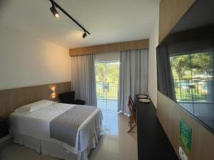a hotel room with a bed and a large window at DR Hotel Rio Branco do Sul in Votuverava