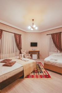 a bedroom with two beds and a desk with a television at Pigeon Valley Hotel in Uchisar