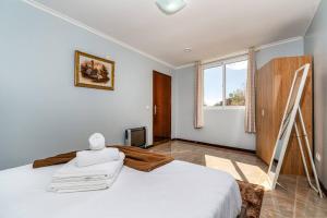 een slaapkamer met een groot wit bed en een raam bij Noite's House I - Prazeres in Prazeres