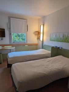 a hotel room with two beds and a window at ibis budget Saint-Omer Centre in Saint-Omer
