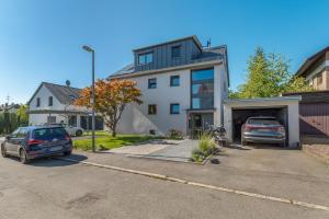 a house with two cars parked in a driveway at NEU: Stylische Suite mit Netflix und Workspace in Böblingen