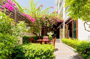 a garden with a table and chairs and flowers at Cozy Savvy Boutique Hotel Hoi An in Hoi An