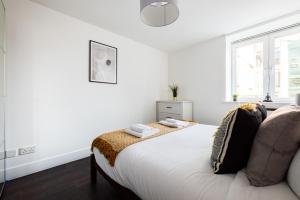 a white bedroom with a bed and a window at The Waterloo Apartments in London