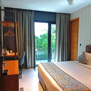 a bedroom with a bed and a desk and a window at Hotel Bluestone - Nehru Place in New Delhi