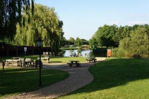 einen Park mit Picknicktischen und einem Teich im Hintergrund in der Unterkunft Queen's Head Inn in Nassington