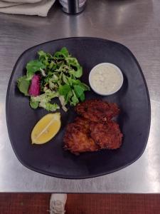 a black plate of food with a salad and a lemon at Queen's Head Inn in Nassington