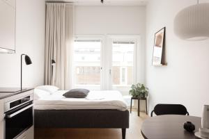 a white bedroom with a bed and a window at Noli Katajanokka II in Helsinki