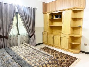 1 dormitorio con armario de madera y cama en Evergreen Apartment, en Murree