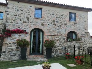 MonteneroにあるVECCHIO CASALE QUERCETINO - ANDRONEの黒い扉と花の石造りの家