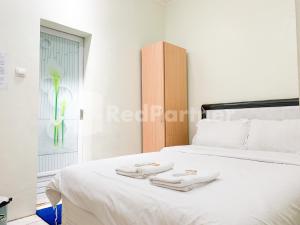 - une chambre avec un lit blanc et des serviettes dans l'établissement Oma Uti Syariah Mitra RedDoorz near Stasiun Lempuyangan, à Sentool
