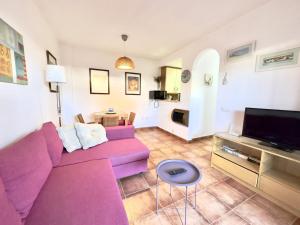 sala de estar con sofá púrpura y TV en ARRECIFE Apartment Rota by Cadiz4Rentals en Rota