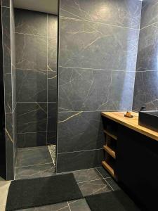 a bathroom with a shower with black marble tiles at L'Opale - L'Entre Vous - Spa in Les Attaques +15 photos