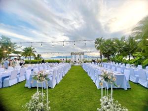 une rangée de tables avec des chaises blanches et des fleurs dans l'établissement Alibu Resort Nha Trang, à Nha Trang 254 autres photos