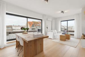 a white living room with a table and some windows at Julias Rooftop stay in Knokke-Heist