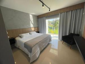 um quarto com uma cama e uma grande janela em DR Hotel Rio Branco do Sul em Votuverava