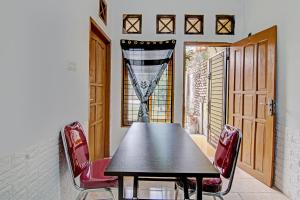 une salle à manger avec une table noire et des chaises rouges dans l'établissement SPOT ON 92801 Penginapan Puti Syariah, à Pekanbaru