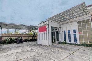 - un bâtiment blanc avec un solarium en haut dans l'établissement SPOT ON 92801 Penginapan Puti Syariah, à Pekanbaru